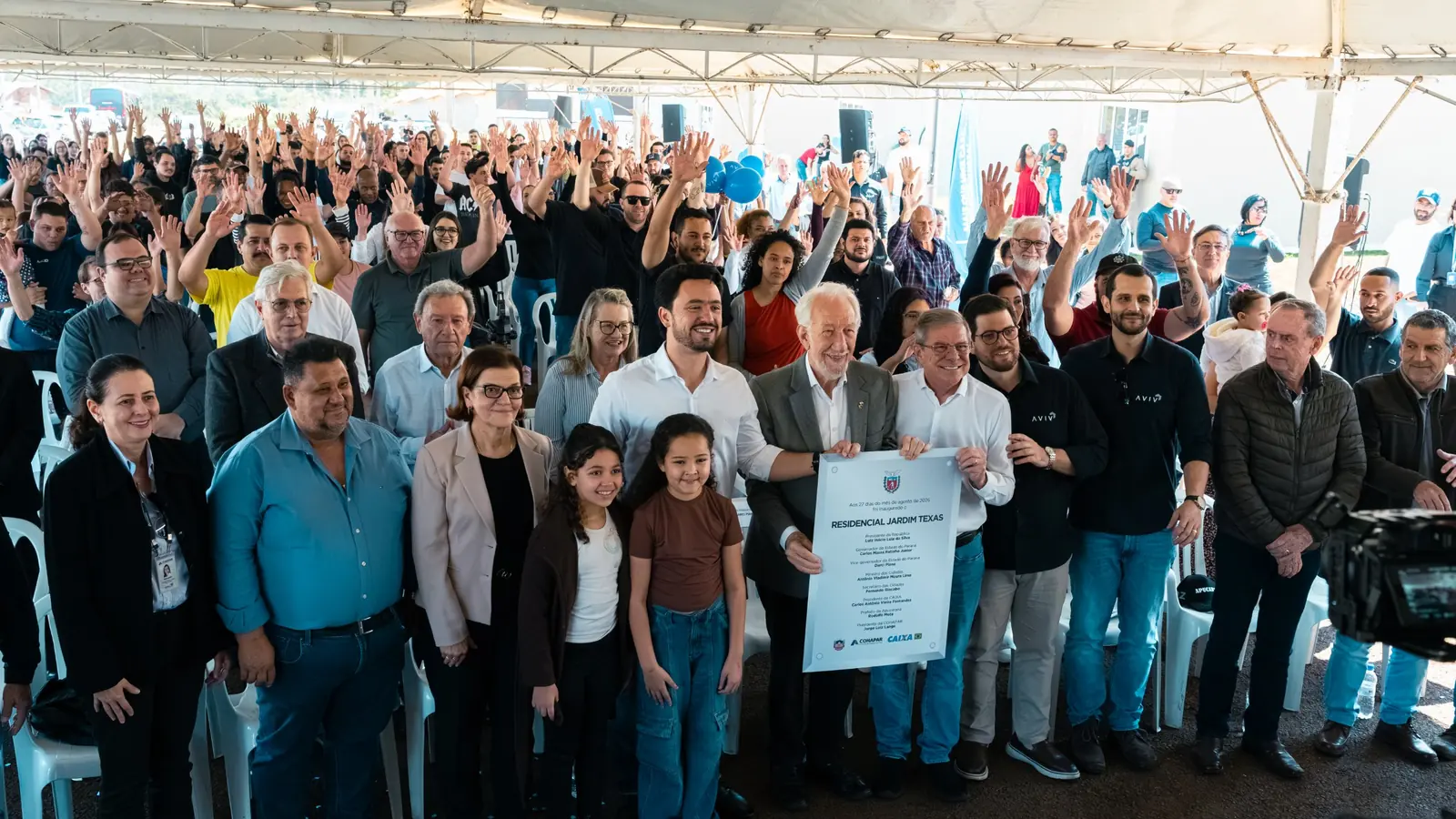 Inauguração do Residencial Jardim Texas, com moradores e autoridades de braços para o alto
